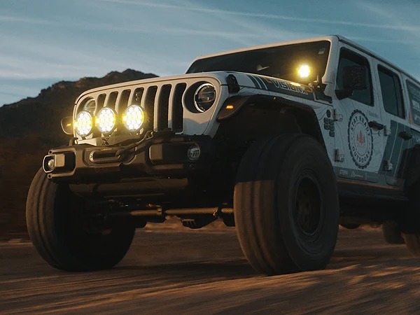 Jeep Wrangler with LED ditch lights and light bar illuminated on trail
